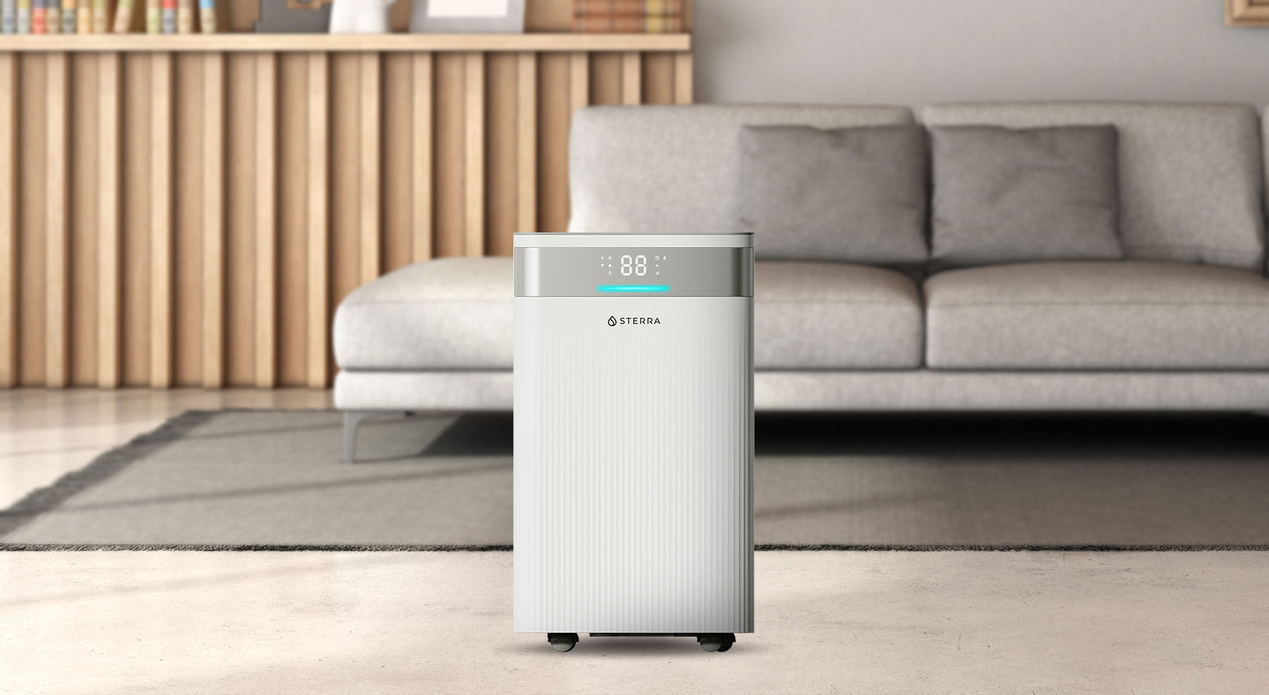 A modern air purifier in a living room with a gray couch and wooden bookshelf.